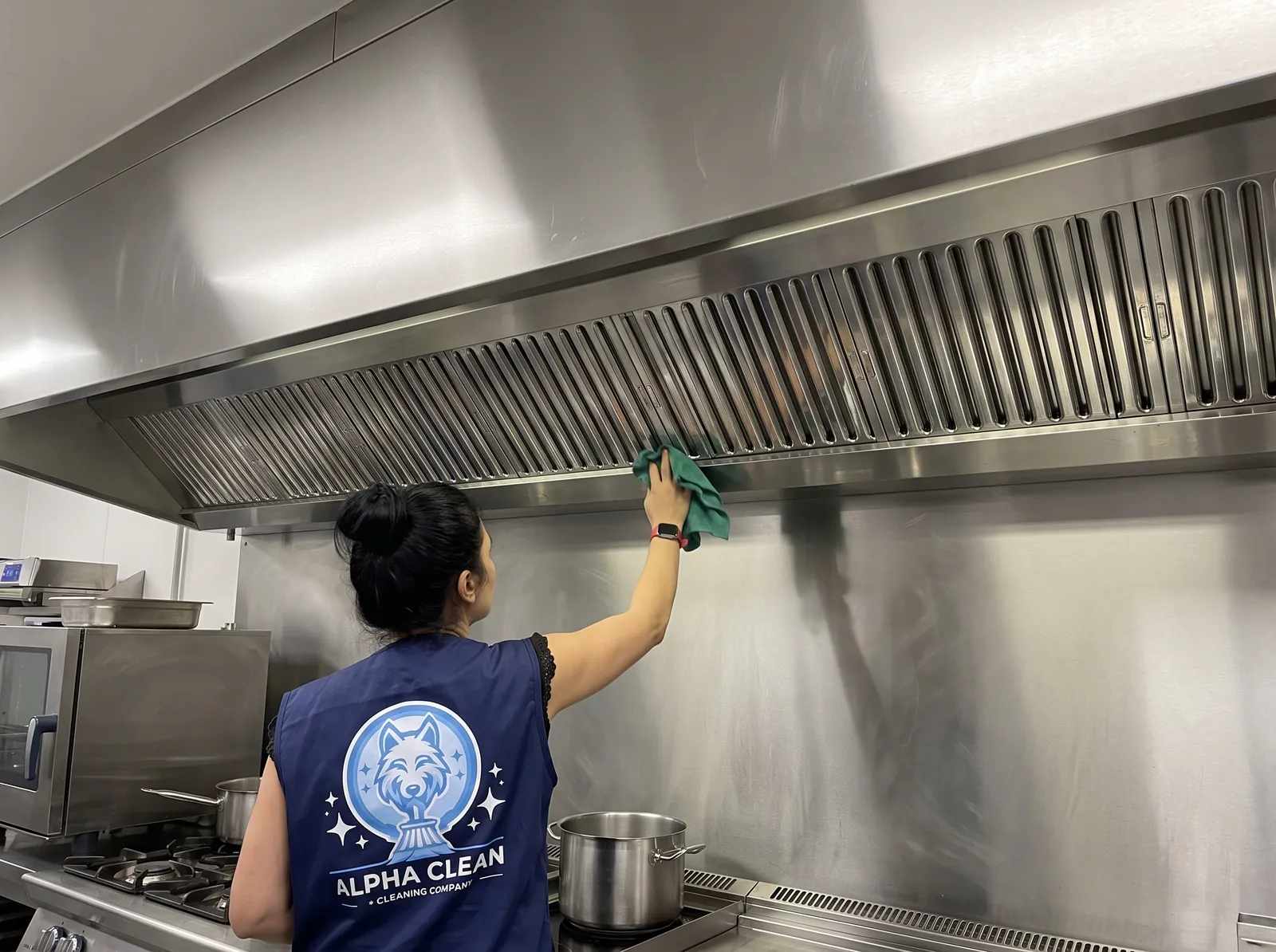 Agente Alpha Clean nettoyant une hotte inox en cuisine professionnelle